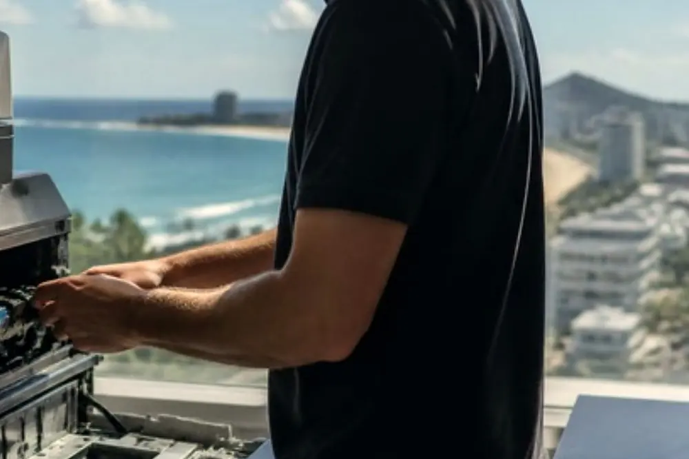 Technician servicing a copier beside a window in a bright Sunshine Coast office
